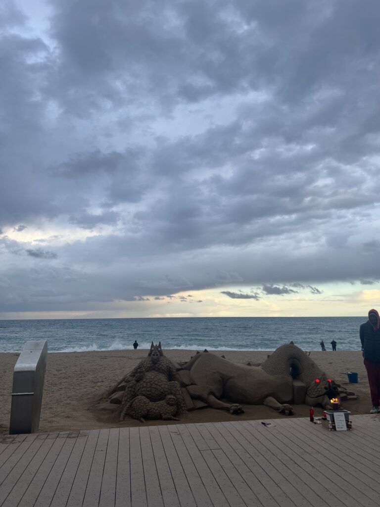 Scultura fatta di sabbia di un drago sulla spiaggia della Barceloneta 