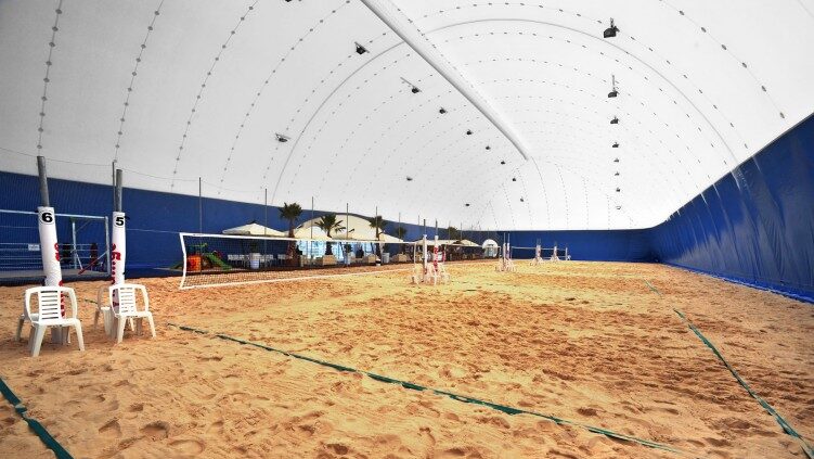 tenso-struttura coperta con tendone a volta bianco e blu, contenente sei campi da beach volley uno adiacente all'altro
