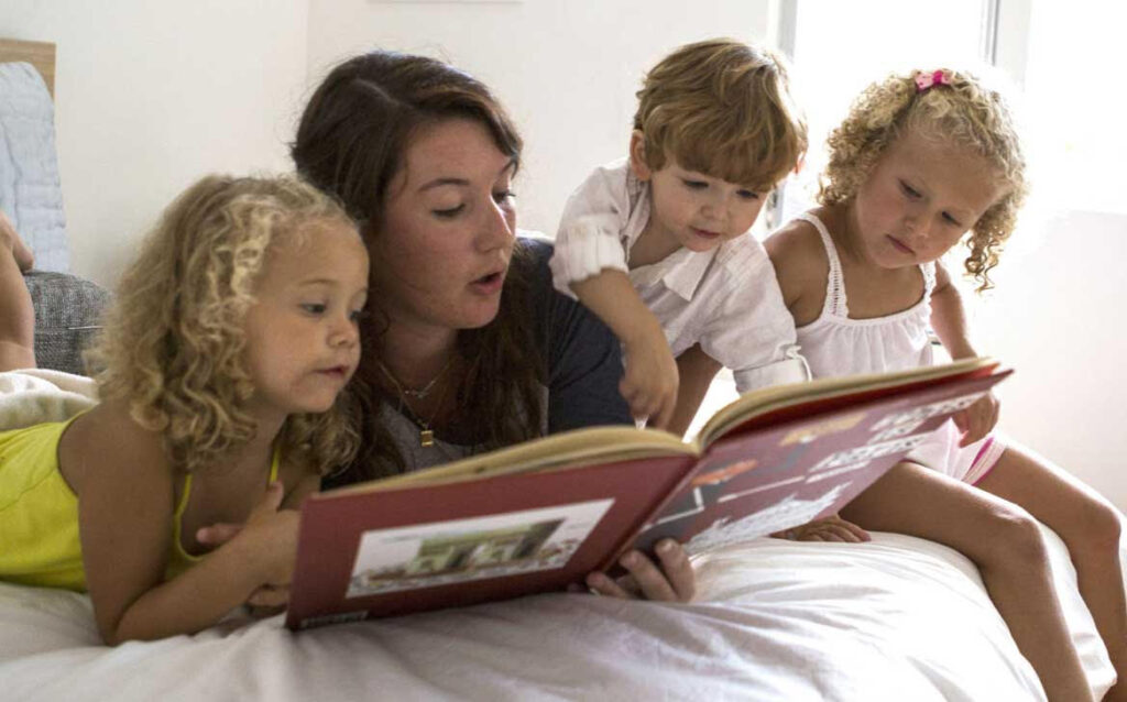 Ragazza alla pari che legge una storia alle bambine. 