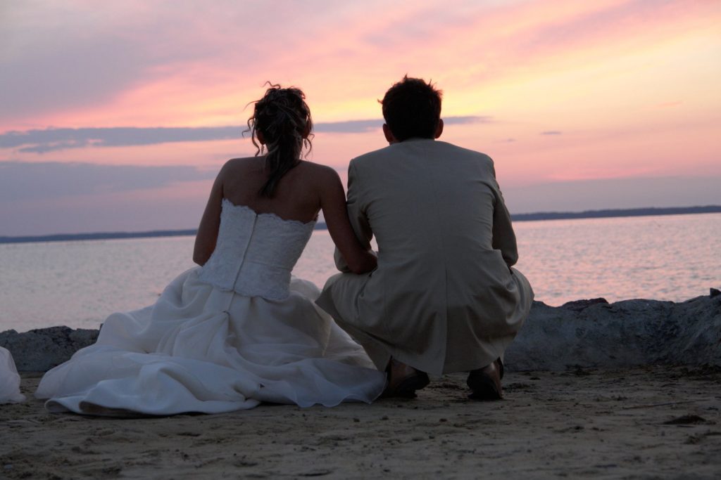 coppia di novelli sposi in spiaggia per un vaggio di nozze sostenibile
